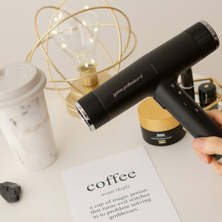 Friseursalon Daniela Blaubeuren Stillleben mit Friseurgegenständen. Ein Fön, ein Kaffee, eine Lampe, arrangiert auf einem Tisch.